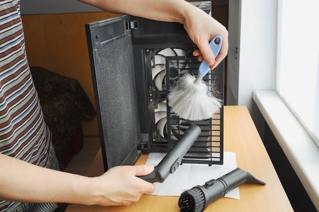 A person using compressed air to clean the inside of a desktop computer. Dust particles are visible being blown away from the components. The focus is on the motherboard and cooling fans.